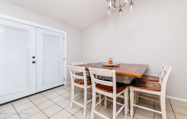 dining room featuring lofted ceiling, an inviting chandelier, and light tile patterned floors