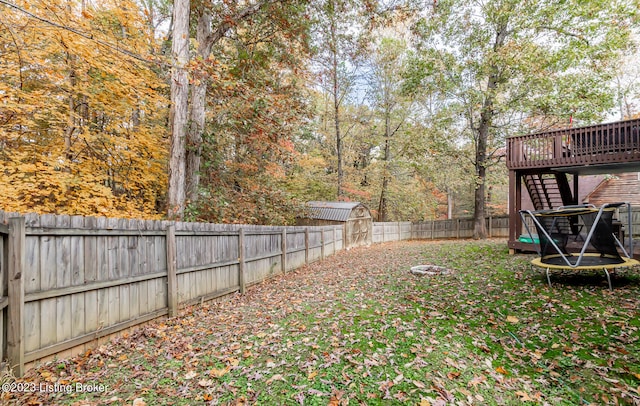 view of yard featuring a storage shed, a wooden deck, and a trampoline