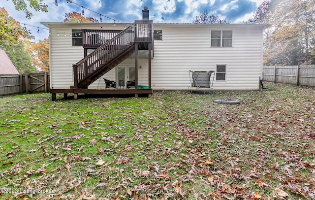 rear view of property featuring a wooden deck and a lawn