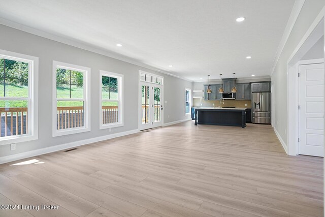 unfurnished living room with crown molding and light wood-type flooring