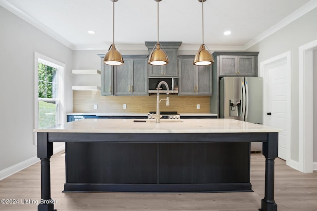 kitchen featuring stainless steel appliances, light stone countertops, backsplash, and a kitchen island with sink