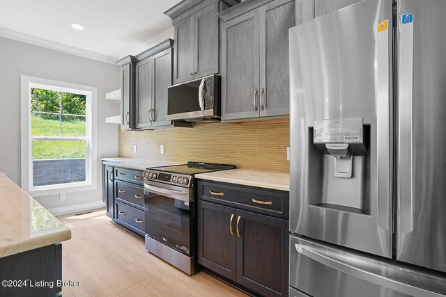 kitchen with light wood-type flooring, appliances with stainless steel finishes, and tasteful backsplash