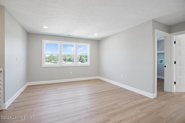 spare room featuring a textured ceiling and light hardwood / wood-style flooring