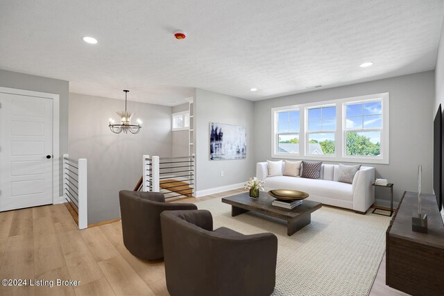 living room featuring a textured ceiling, light hardwood / wood-style flooring, and a chandelier