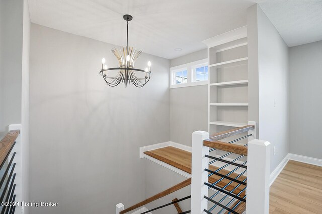 stairs featuring hardwood / wood-style flooring and an inviting chandelier