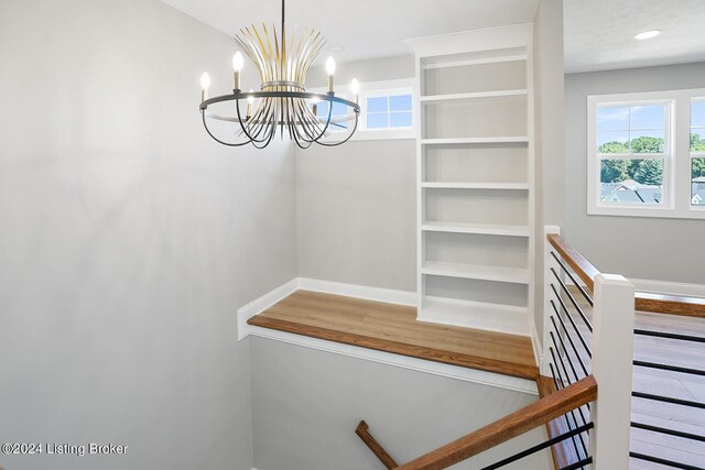 staircase featuring hardwood / wood-style floors and an inviting chandelier