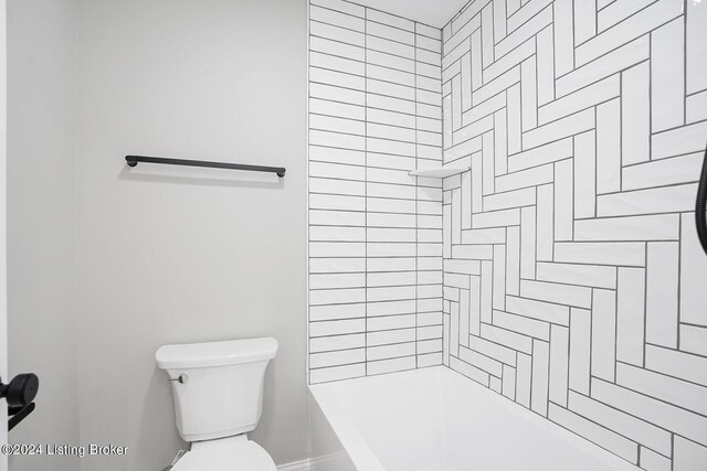 bathroom with tiled shower / bath combo and toilet