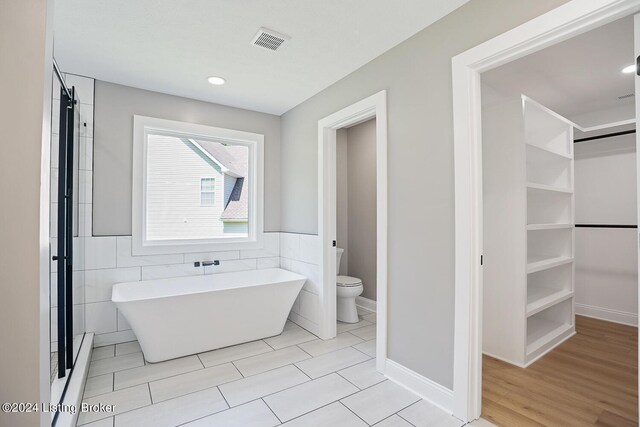 bathroom featuring tile walls, toilet, separate shower and tub, and tile patterned floors