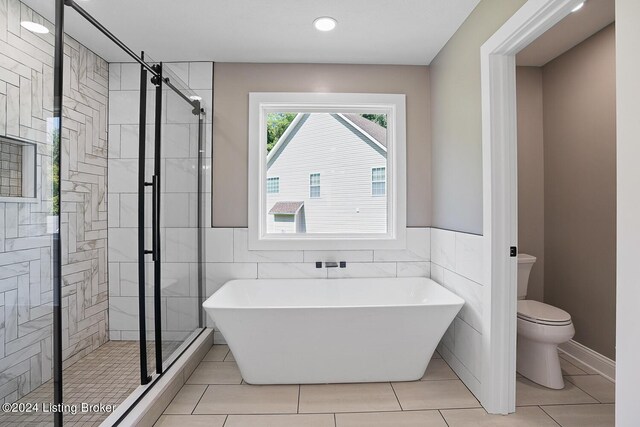 bathroom featuring plus walk in shower, tile walls, tile patterned flooring, and toilet