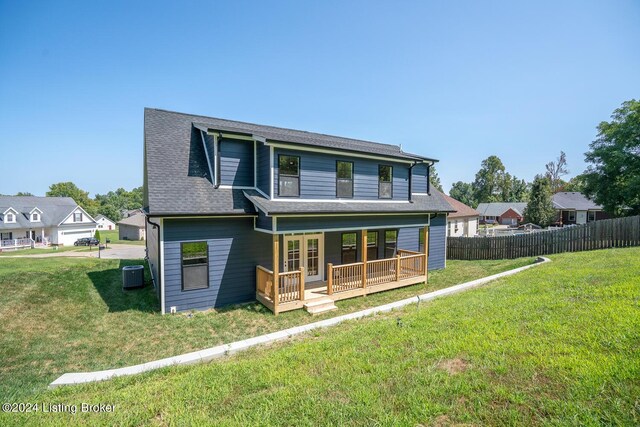 view of front of house with a porch, a front yard, a garage, and central air condition unit