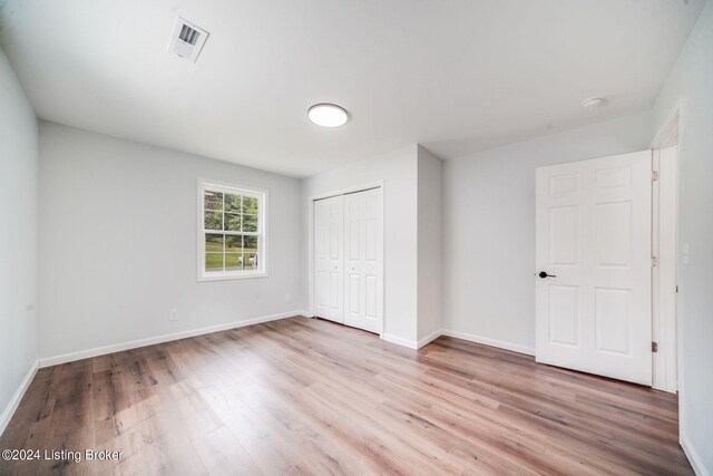 unfurnished bedroom with light hardwood / wood-style flooring and a closet