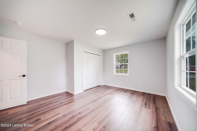 unfurnished bedroom with multiple windows, light hardwood / wood-style flooring, and a closet