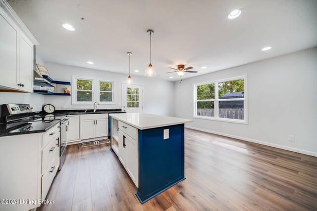 kitchen with electric stove, ceiling fan, a center island, and white cabinets