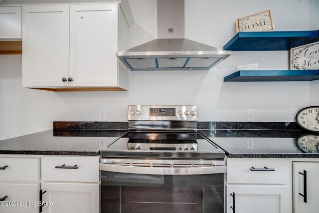 kitchen with white cabinetry, stainless steel range with electric cooktop, wall chimney exhaust hood, and dark stone countertops