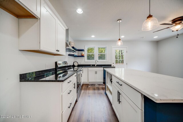 kitchen featuring dark stone counters, white cabinetry, hanging light fixtures, and stainless steel range with electric cooktop