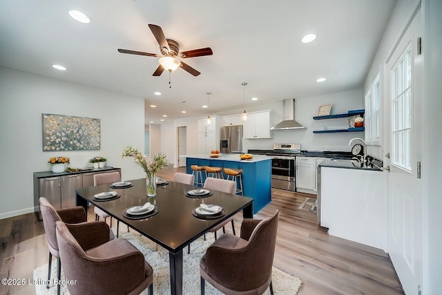 dining space with ceiling fan, light hardwood / wood-style flooring, and sink