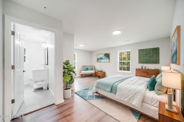 bedroom featuring ensuite bathroom and light hardwood / wood-style flooring