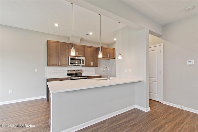 kitchen featuring stainless steel appliances, a sink, dark wood-type flooring, backsplash, and recessed lighting