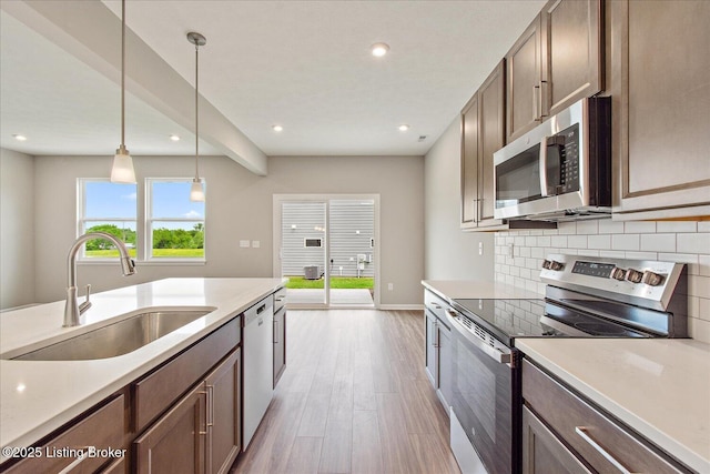 kitchen featuring appliances with stainless steel finishes, a sink, light wood-style flooring, decorative backsplash, and recessed lighting