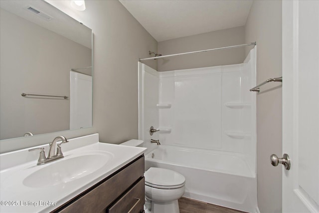 bathroom with toilet, vanity, wood finished floors, and  shower combination