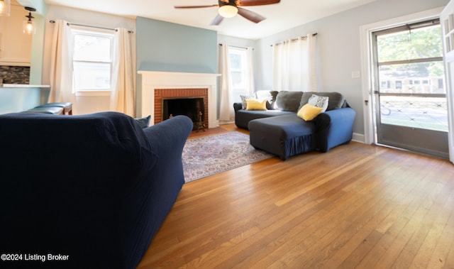 living room with a fireplace, a wealth of natural light, wood-type flooring, and ceiling fan