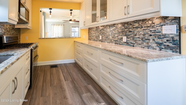 kitchen featuring appliances with stainless steel finishes, decorative backsplash, dark hardwood / wood-style flooring, and ceiling fan