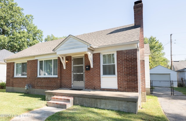 bungalow-style home featuring a garage, a front yard, and an outbuilding