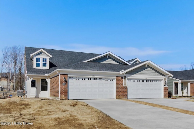 view of front of house with a garage, brick siding, central AC, and concrete driveway