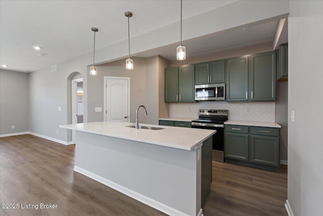 kitchen with tasteful backsplash, arched walkways, dark wood-type flooring, stainless steel appliances, and a sink