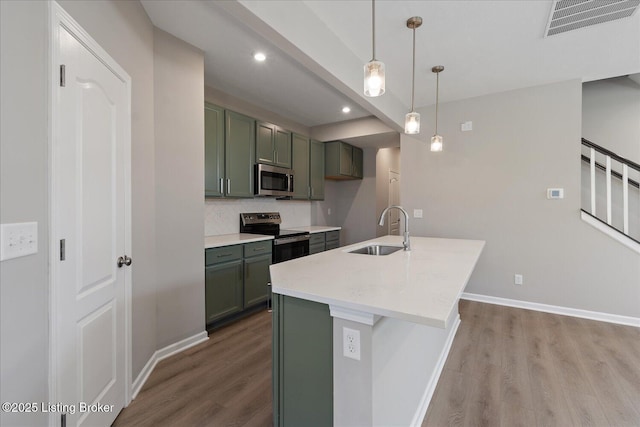 kitchen featuring light wood finished floors, green cabinetry, appliances with stainless steel finishes, and a sink