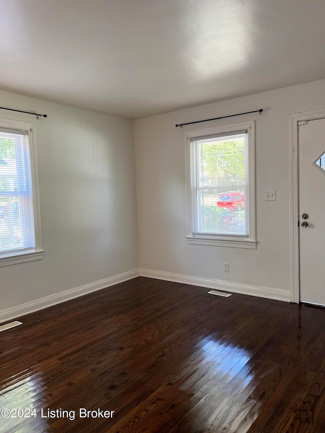 empty room with dark hardwood / wood-style flooring and a healthy amount of sunlight