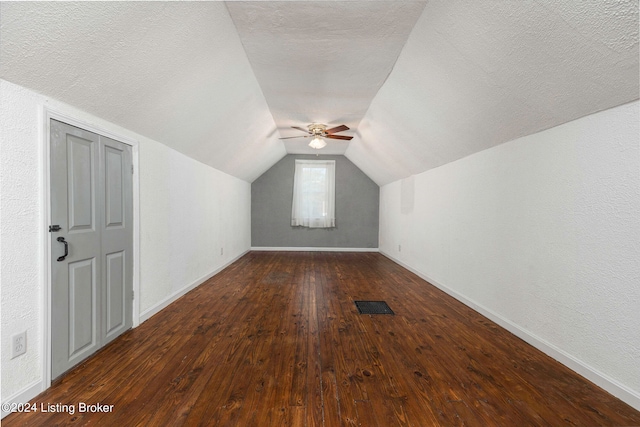 additional living space with a textured ceiling, dark wood-type flooring, ceiling fan, and vaulted ceiling