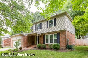 view of front facade with driveway, brick siding, an attached garage, fence, and a front yard