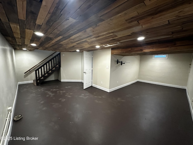 finished below grade area featuring wood ceiling, stairs, and baseboards