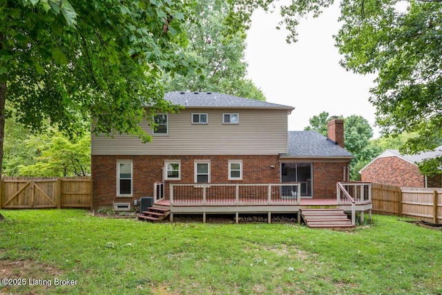 back of property with brick siding, a fenced backyard, a lawn, and a wooden deck