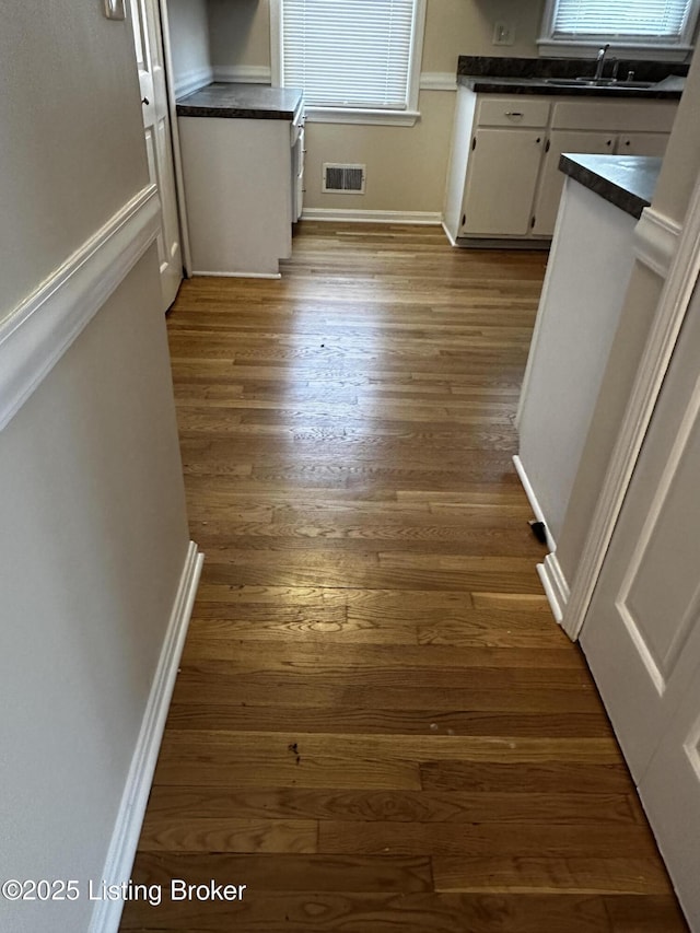 interior space featuring visible vents, dark wood finished floors, white cabinets, dark countertops, and a sink