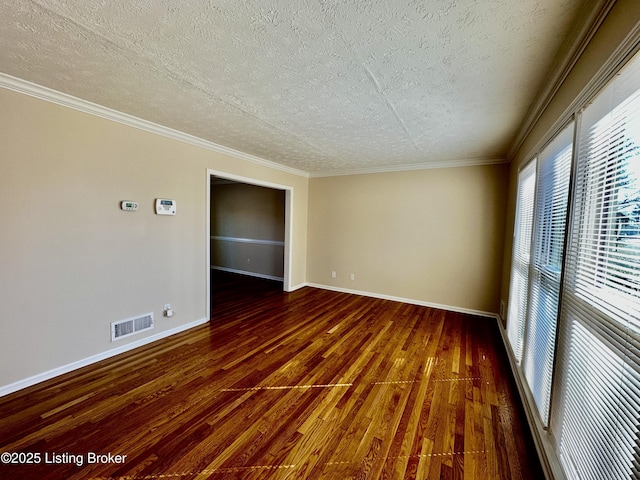 unfurnished room featuring dark wood-style floors, visible vents, ornamental molding, a textured ceiling, and baseboards