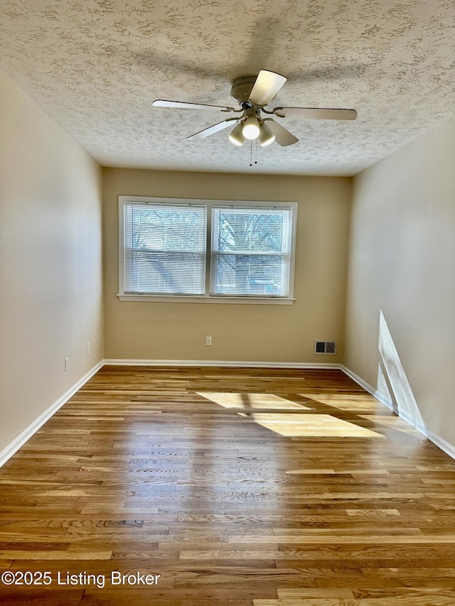 unfurnished room featuring a textured ceiling, light wood-style flooring, and visible vents