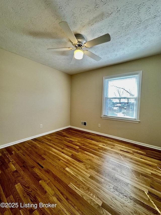 empty room featuring baseboards, a textured ceiling, visible vents, and wood finished floors