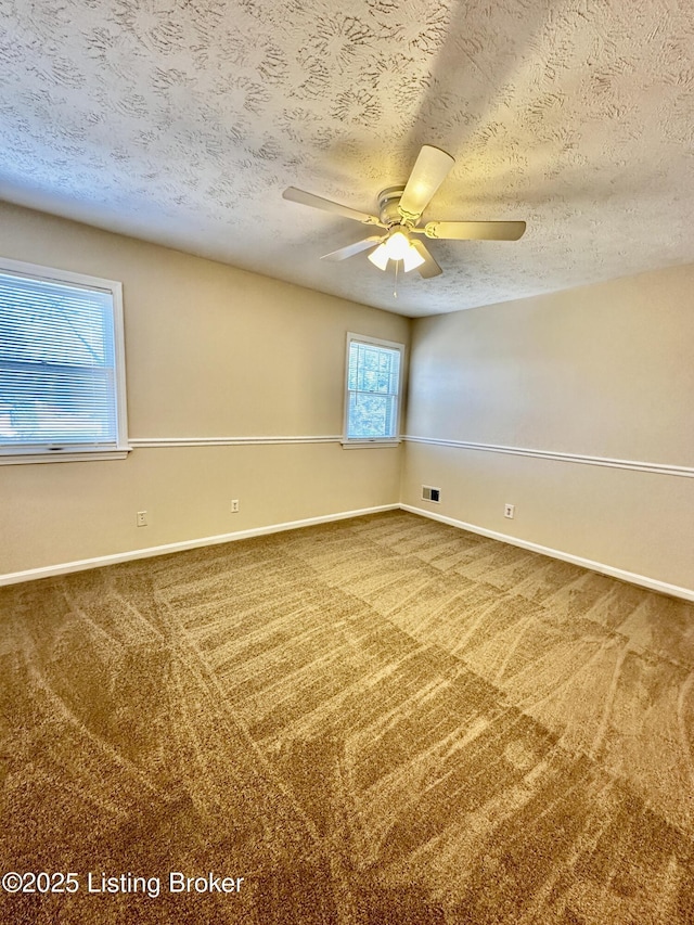 spare room featuring carpet floors, a textured ceiling, baseboards, and a ceiling fan