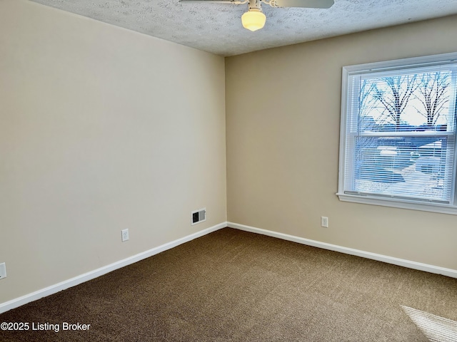 spare room featuring carpet floors, baseboards, visible vents, and a textured ceiling