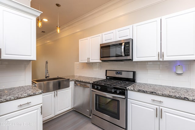 kitchen with pendant lighting, crown molding, appliances with stainless steel finishes, hardwood / wood-style flooring, and white cabinets