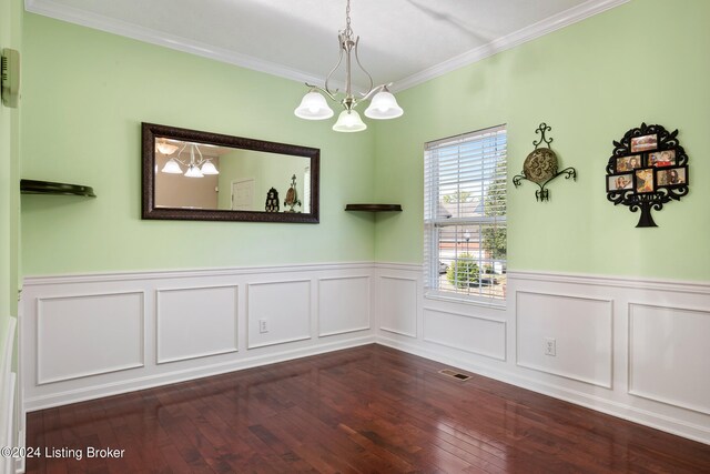 unfurnished dining area featuring dark wood-type flooring, ornamental molding, and an inviting chandelier