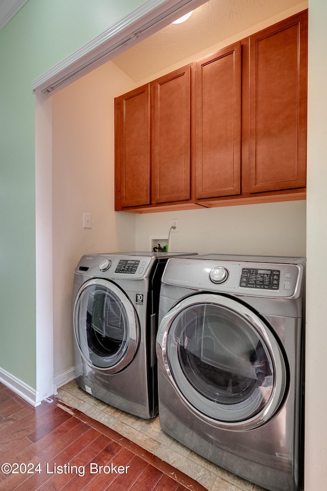 washroom with washing machine and clothes dryer, cabinets, dark hardwood / wood-style floors, and ornamental molding