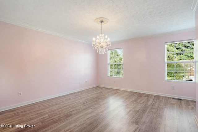 spare room featuring a textured ceiling, a notable chandelier, wood-type flooring, and ornamental molding