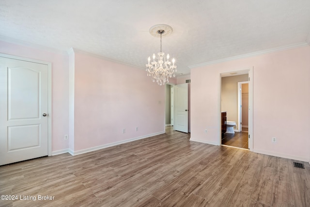 unfurnished room with light hardwood / wood-style flooring, ornamental molding, and a notable chandelier