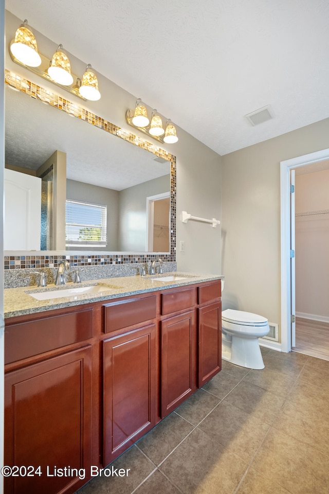 bathroom with tile patterned flooring, vanity, tasteful backsplash, and toilet