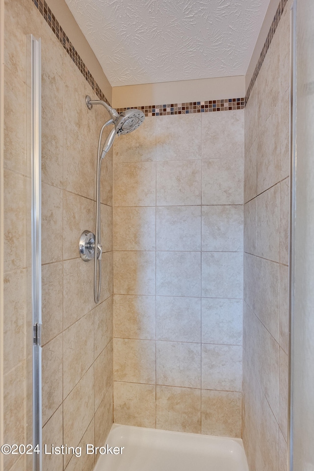 bathroom with tiled shower and a textured ceiling