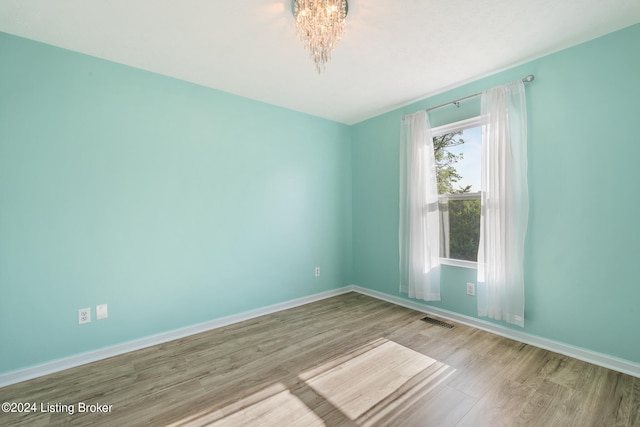 empty room featuring light hardwood / wood-style floors and an inviting chandelier