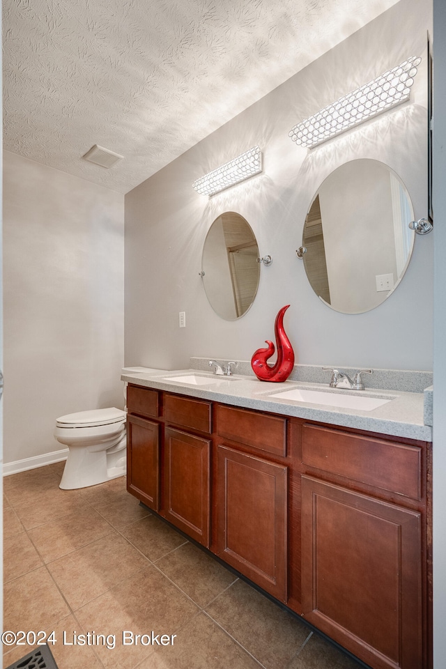 bathroom featuring tile patterned flooring, vanity, toilet, and a textured ceiling